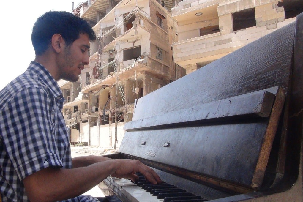 Aeham al-Ahmad, a former resident of Damascus' Yarmuk Palestinian refugee camp, plays the piano in the middle of the street. Photo: AFP