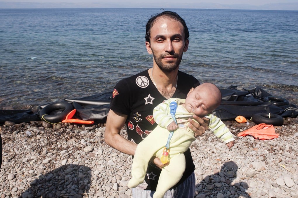 A man holds a baby as refugees arrive on the shore of Sykamias beach, west of the port city of Mytilini, after crossing the Aegean sea from Turkey. Photo: AFP