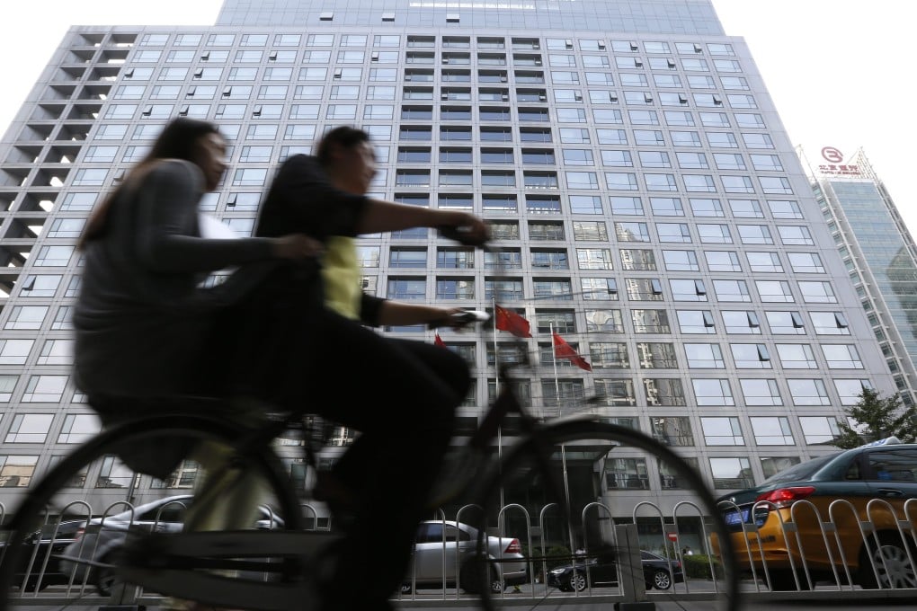 Cyclists pedal past the China Securities Regulatory Commission building in Beijing. Photo: EPA