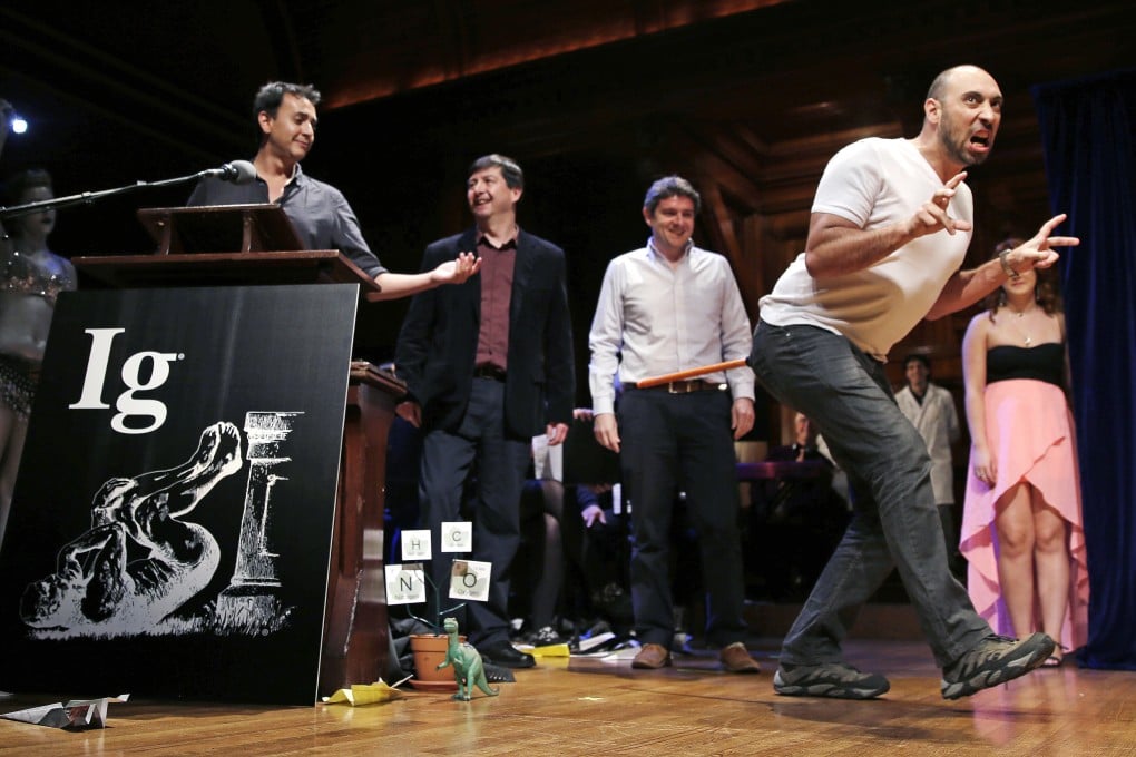 Bruno Grossi, a researcher from Chile, shows how a chicken would walk like a dinosaur with a weighted stick attached to its tail. He and fellow researchers won the biology prize. Photo: AP
