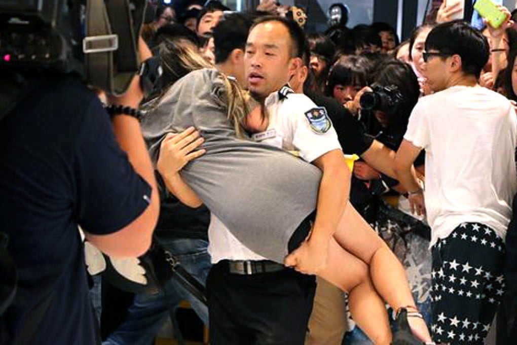 The unnamed guard carries away the woman who collapsed at event for Korean movie stars. Photo: Sina