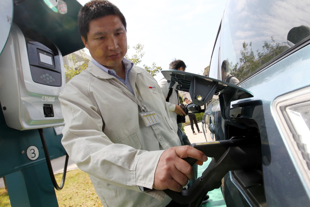 An employee of Chinese automaker BYD demonstrates how to use an EV charging at the company's headquarters in Shenzhen, Guangdong province. Photo: May Tse