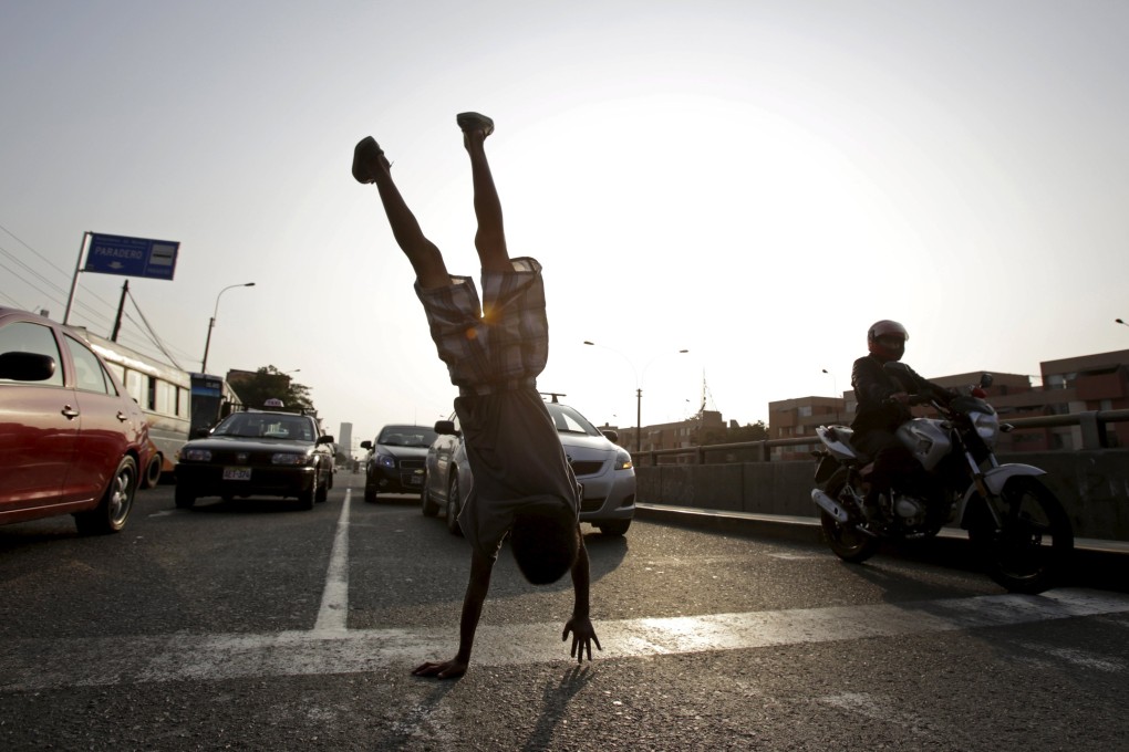 A boy somersaults at a traffic junction in Lima. Poverty drives some children to perform on streets in Peru to make a living from tips given by drivers. Photo: Reuters