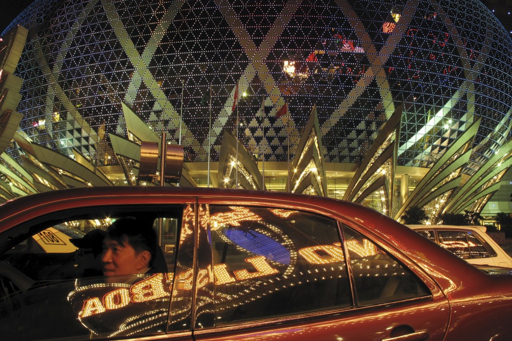 A passenger sits in a car reflecting Casino Lisboa in Macau. Photo: Reuters