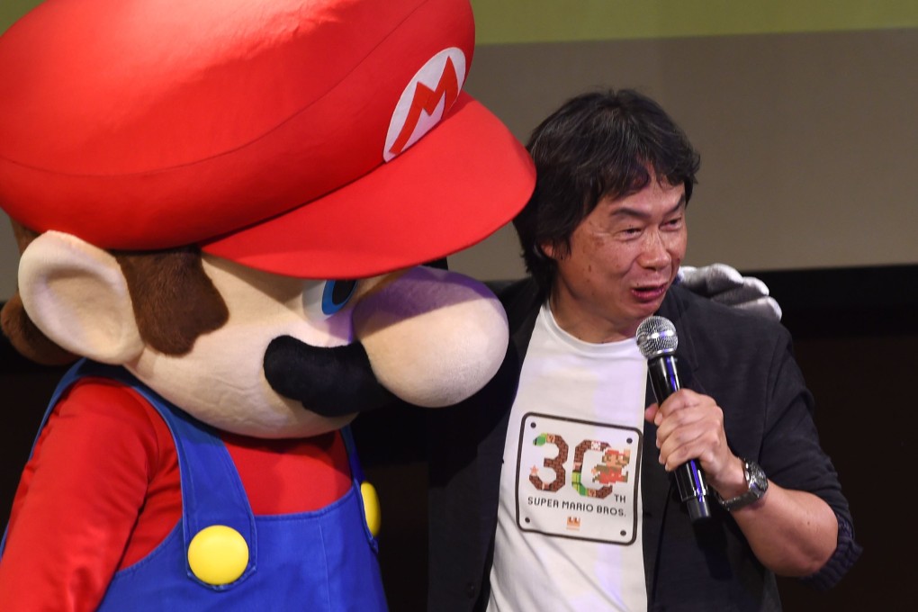 Nintendo game creator Shigeru Miyamoto (poses with his character Super Mario  during a live performance of the most well-known Mario music to mark the game's 30th anniversary in Tokyo. Photo: AFP