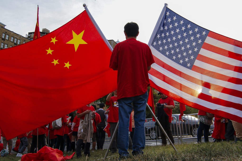A man holds up China and the United States' national flags in Washington on Thursday. Photo: EPA