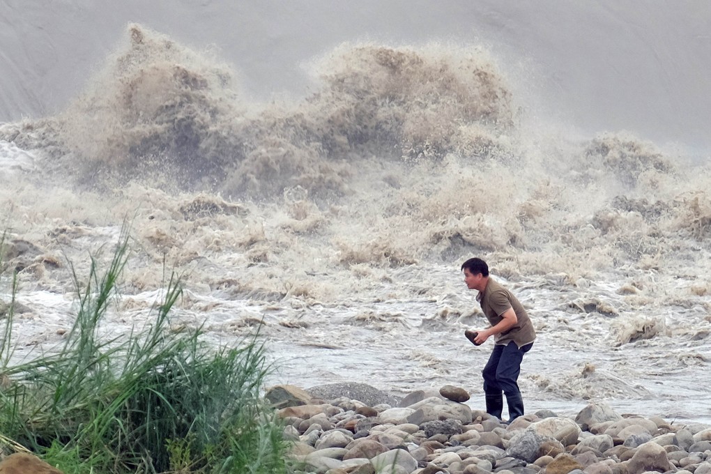A man battles to stand up beside the Xindian river as Typhoon Dujuan continues to batters Taipei on Tuesday morning. Photo: AFP