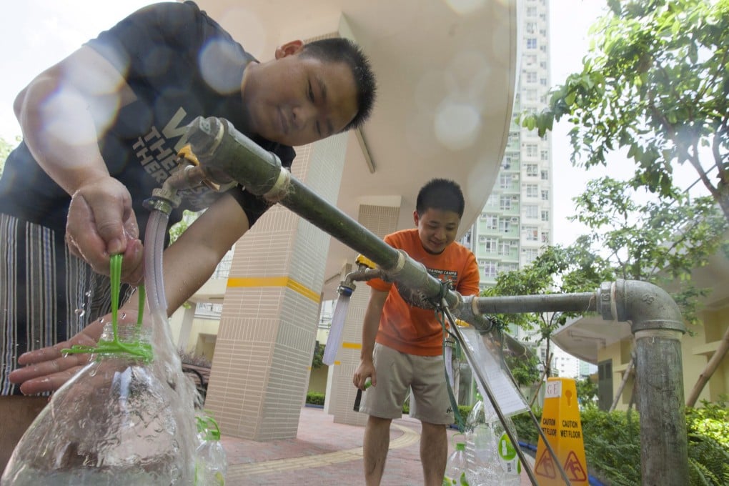 Residents of Kai Ching Housing Estate fill up containers with drinking water from a temporary pipe in the street. Photo: EPA