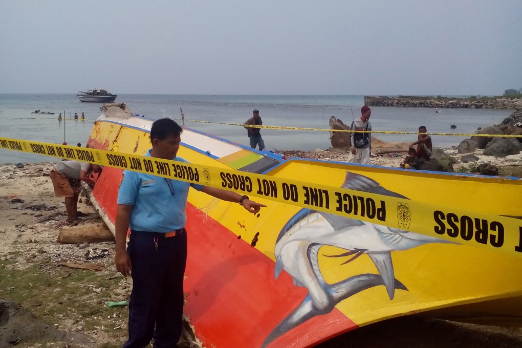 A policeman points to a boat allegedly used by the kidnappers of three foreigners and a Filipina on Samal island, found abandoned in Jolo island.  Photo: AFP