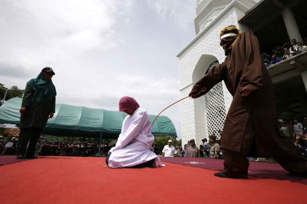 An Acehnese woman is whipped in public for violation Sharia law. Two lesbians where spared the cane because a new criminal code that criminalises homosexuality won’t take effect until later this month. Photo: EPA