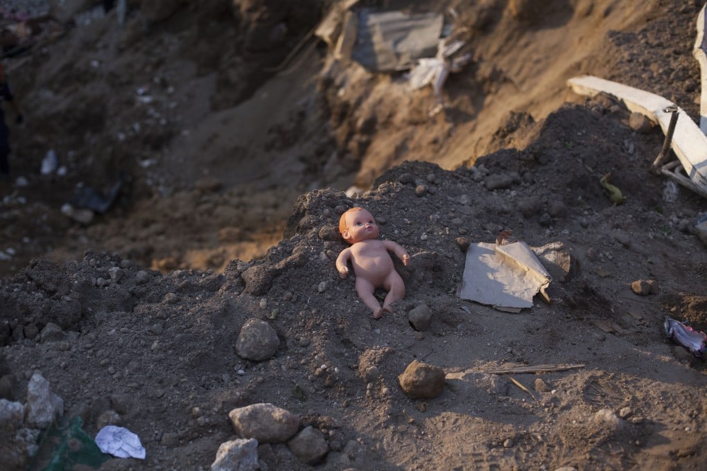 A doll lays in the dirt where a landslide occurred in the village of El Cambray II. Among the confirmed dead were 17 children. Photo: Xinhua