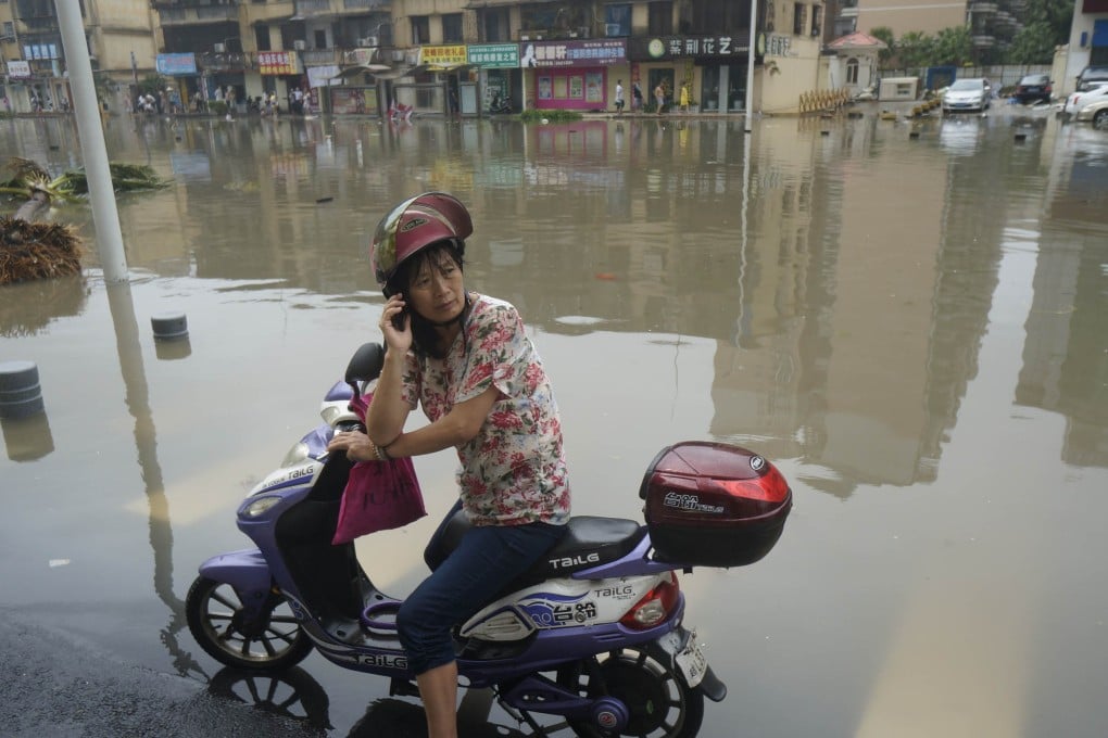 A motorcyclist makes a phone call after stopping on the flooded main street of Zhanjiang city after Guangdong province was hit by the devastating Typhoon Mujigae. Photo: Xinhua