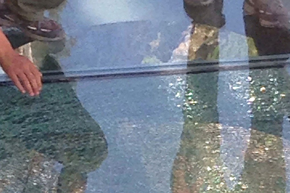 Tourists stand beside a cracked glass tile on the glass-bottomed walkway in China's Yuntaishan in central China's Henan province on Monday, which has now been closed. Photo: AFP