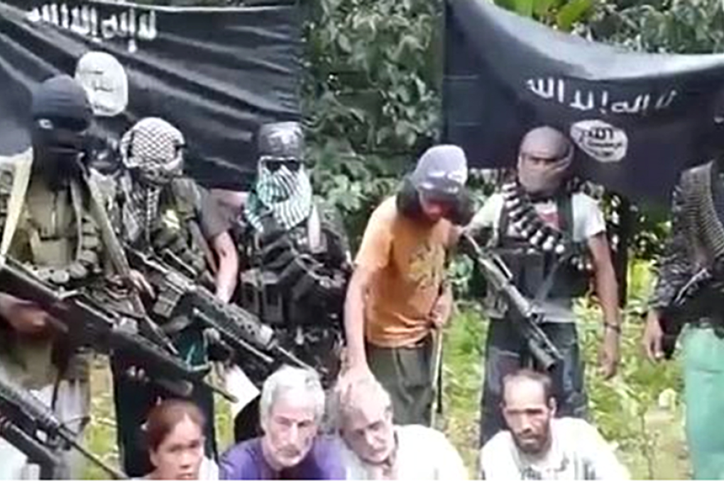 This image taken from a video uploaded to YouTube shows gunmen standing behind John Ridsdel, Robert Hall, Kjartan Sekkingstad, and Hall's partner, Marites Flor, who were kidnapped last month in the southern Philippines.  Photo: YouTube