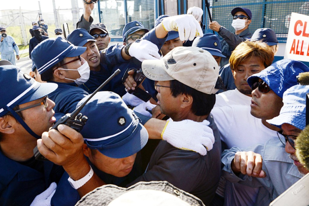 Okinawa locals clash with police outside the fence of Camp Schwab, an American base near a planned relocation site of a US air base, in Nago, Okinawa.  Photo: Kyodo