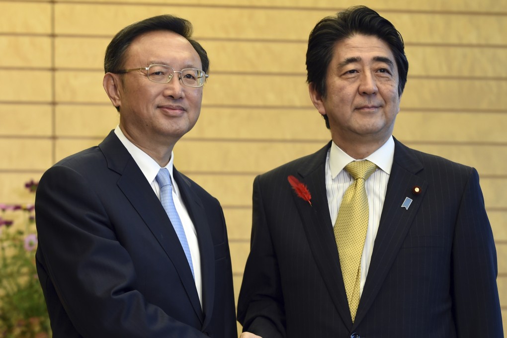 State Councilor Yang Jiechi (left) and Japanese Prime Minister Shinzo Abe shake hands prior to their meeting in Tokyo on Wednesday. Photo: AP