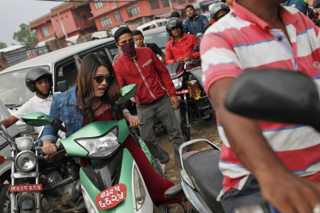 A Nepalese woman pushes her scooter forward as she waits for her turn to fill fuel at a gas station in Kathmandu. Photo: AP