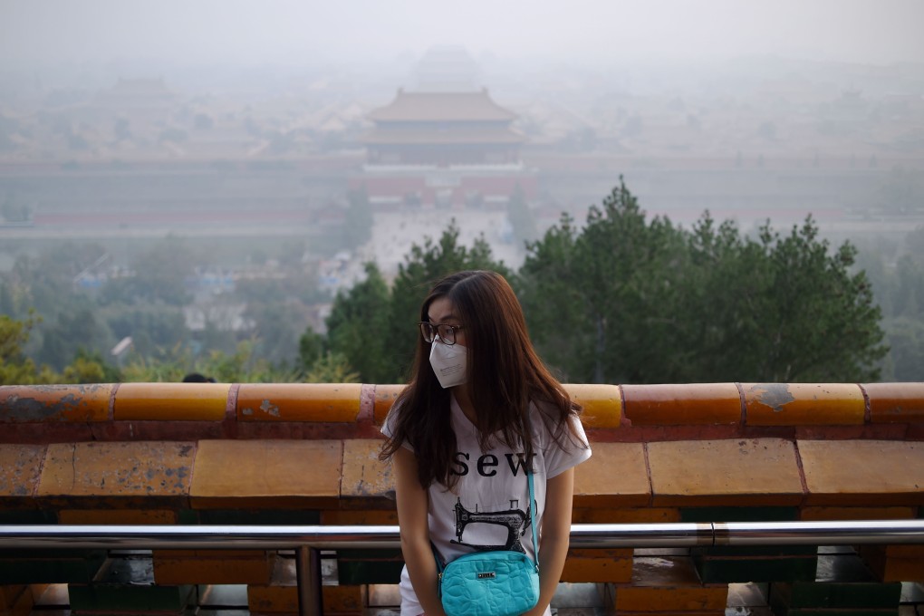 A woman wears a mask as she visits a park near the Forbidden City in Beijing on October 7. Beijing issued a blue warning for air pollution on Friday afternoon, warning the public to reduce outdoor activities and take precautions as the official air quality index reached 344. Photo: AFP