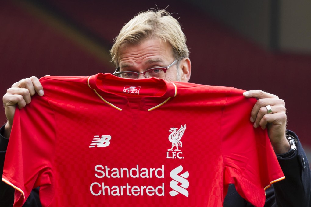 New manager Juergen Klopp hides his face with a shirt as he poses for the press ahead of his debut in charge at Liverpool. Photo: AP
