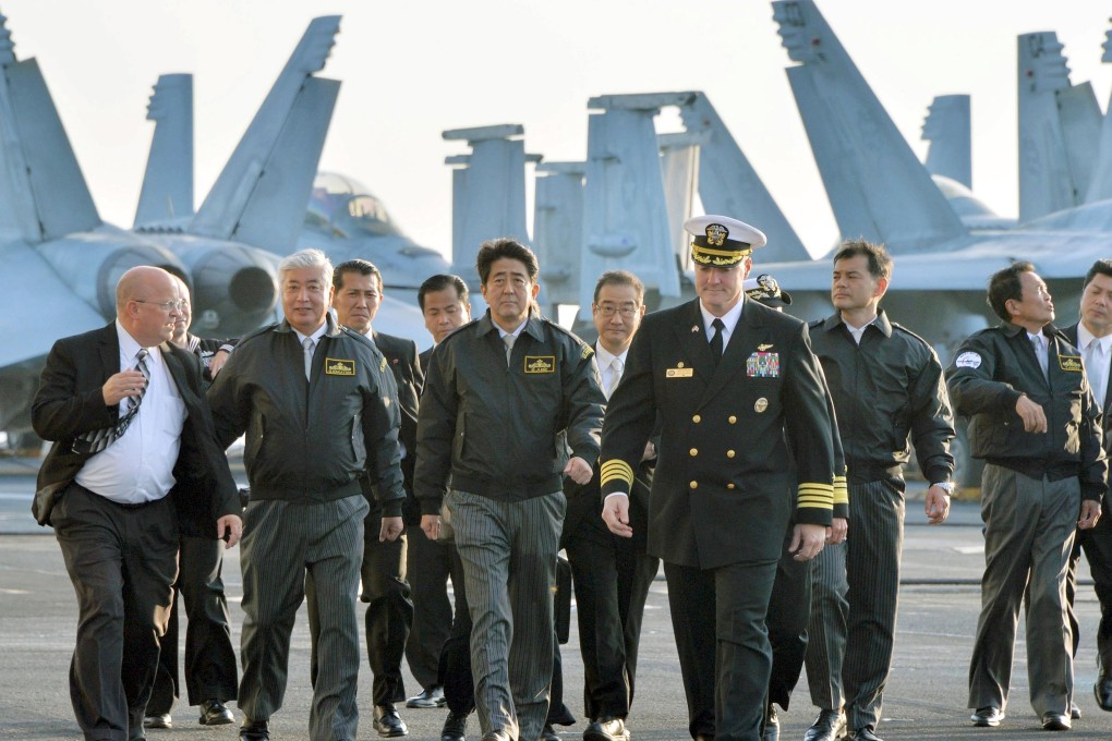 Japan's Prime Minister Shinzo Abe (C), Deputy Prime Minister and Finance Minister Taro Aso (2nd R) and Defence Minister Gen Nakatani (2nd L) walk with Chris Bolt, the captain of the USS Ronald Reagan, a Nimitz-class nuclear-powered super carrier, as they visit the carrier at Sagami Bay.  Photo: Kyodo