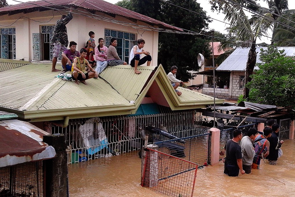 Residents sit on the rooftop of a flooded house in Nueva Ecija province, the Philippines. Photo: Xinhua
