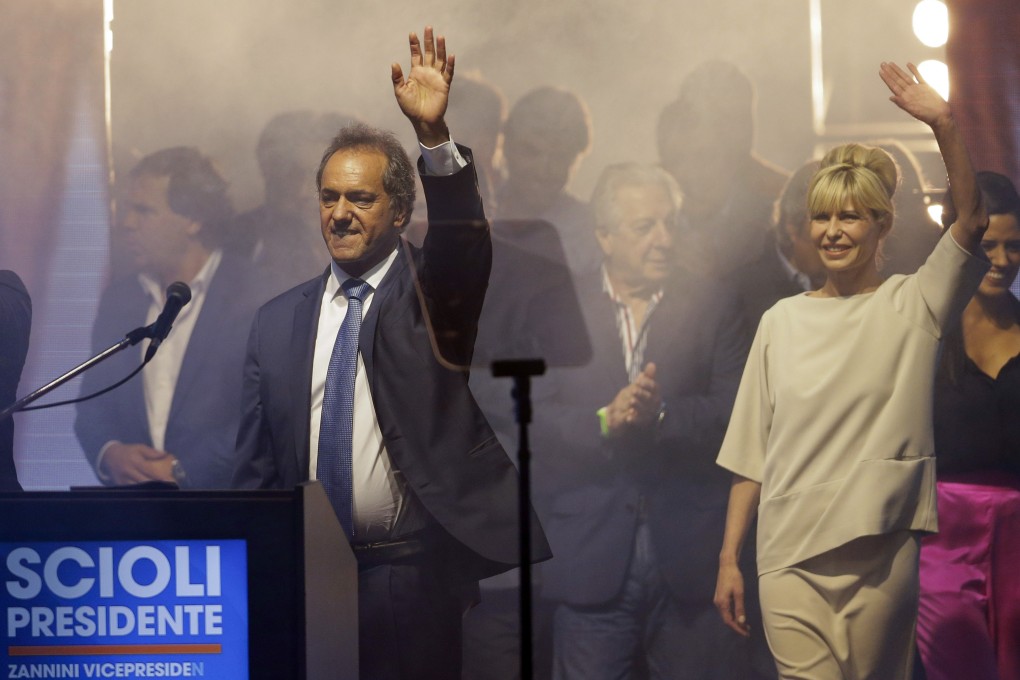 Argentine ruling party presidential candidate Daniel Scioli waves to supporters, next to his wife Karina Rabolini as they walk on stage at the Luna Park stadium in Buenos Aires on Sunday. Photo: AP