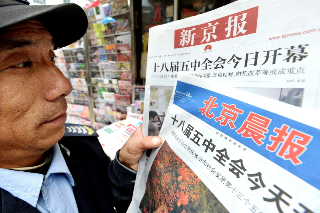 A man in Beijing holds up newspapers covering the opening of the Communist Party plenum to discuss future political policy. Photo: Kyodo