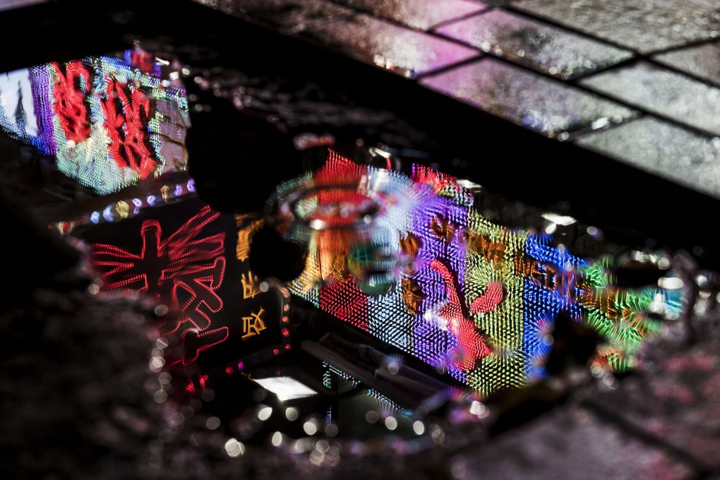 A neon sign for a pharmacy is reflected in water at night. Some pharmacies in Hong Kong have been accused of overcharging tourists. Photo: Bloomberg