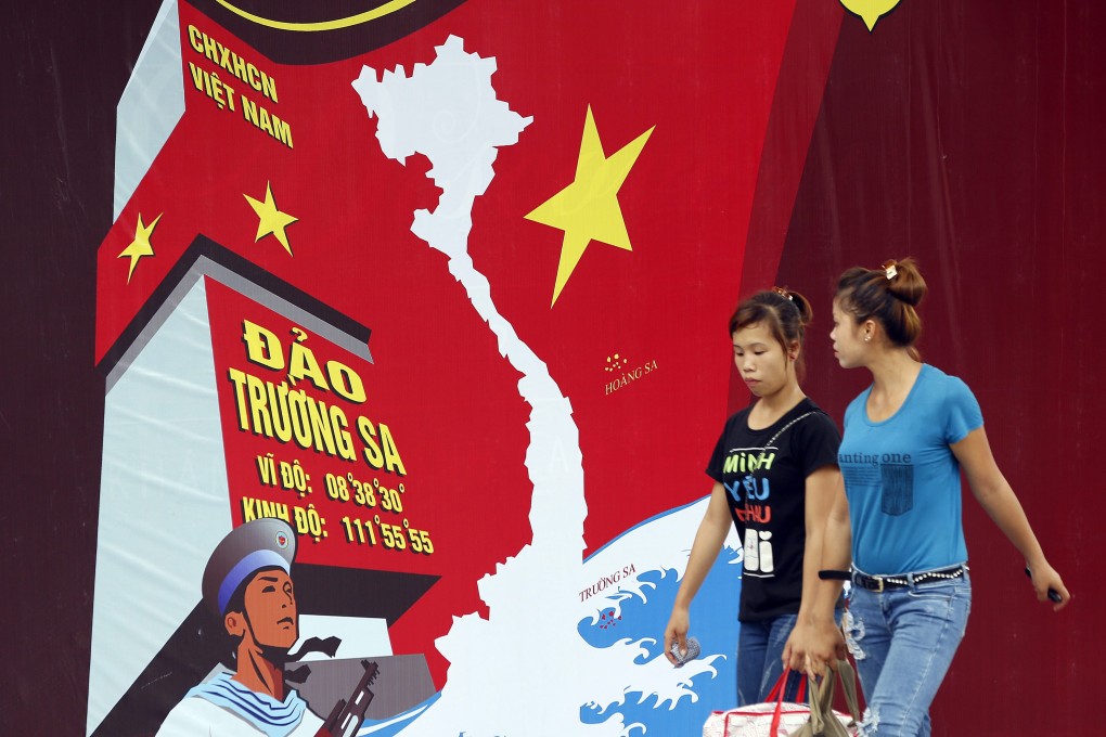 Two women pass a board featuring a map of Vietnam and the words "Spratly Islands" in Hanoi, Vietnam, in a file photo. President Xi Jinping will visit Vietnam next week. Photo: EPA