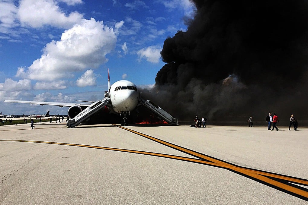 Dense smoke pours from the plane on the tarmac at Fort Lauderdale airport as passengers evacuate on Thursday. Fuel was seen spilling from the aircraft's wing before the fire began. Photo: AFP