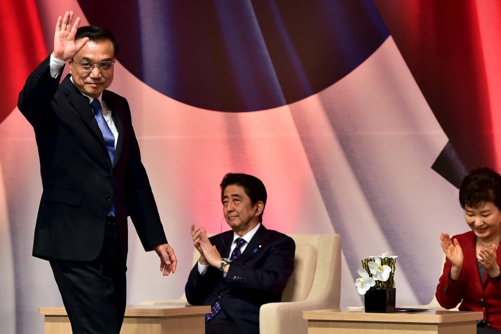 Premier Li Keqiang waves as he walks past Japan's Shinzo Abe and South Korea's Park Geun-hye at a summit in Seoul on Sunday. Photo: Reuters