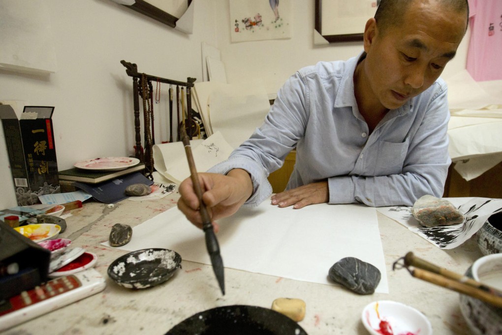 Cartoonist and political satirist Bai Budan dips his brush in ink as he works on a sketch in his studio in central Beijing. He often uses cute and irreverent characters to make his point about social issues but struggles to have his work shown in public. Photo: AP