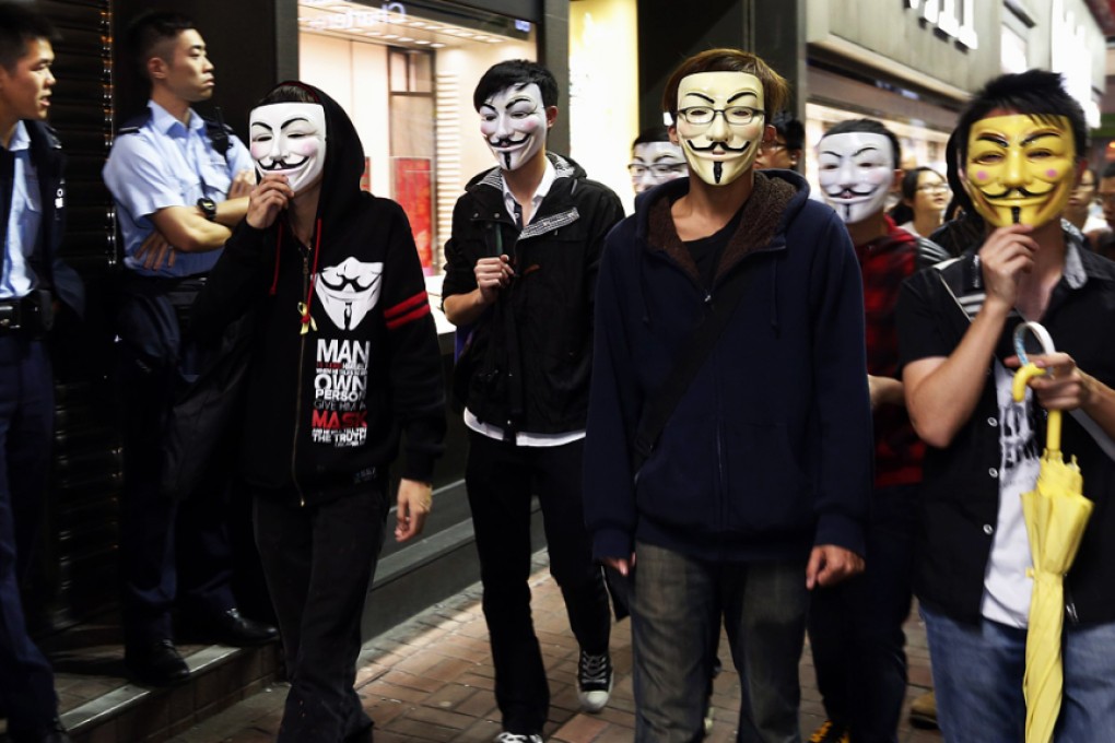 Pro-democracy protesters wearing Guy Fawkes masks walk past policemen on an occupied road in Mong Kok on Guy Fawkes Night last year. Photo: Reuters