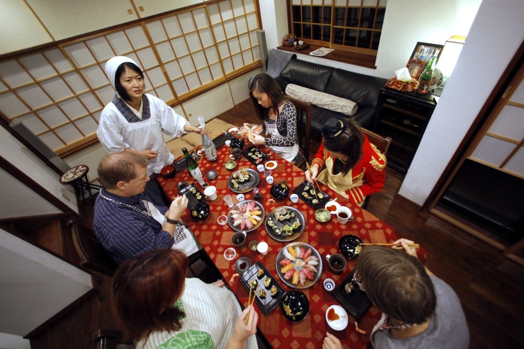 Shino Fukuyama, standing, teaches tourists how to roll sushi at her home in Tokyo