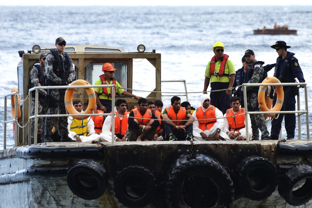 Australian customs officials and navy personnel escort rescued asylum-seekers onto Christmas Island in this 2013 file photo. The Australian immigration detention centre on the island has been hit by rioting. Photo: Reuters