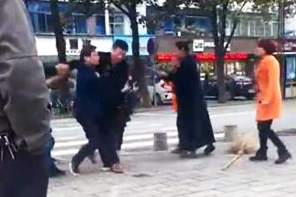 The attacker is held back by bystanders in Zhijiang city in Hubei province. The cleaner was sent to hospital, the police said. Photo: SCMP Pictures