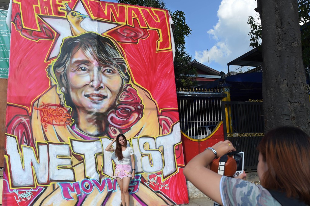 A foreign visitor poses next to a graffiti depiction of Myanmar's opposition leader Aung San Suu Kyi outside the headquarters of the National League for Democracy party in Yangon. Photo: AFP