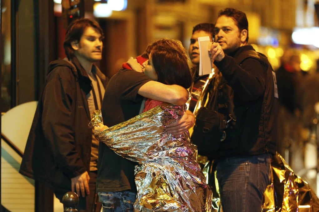 People hug each other before being evacuated by bus, near the Bataclan concert hall in central Paris. Photo: AFP