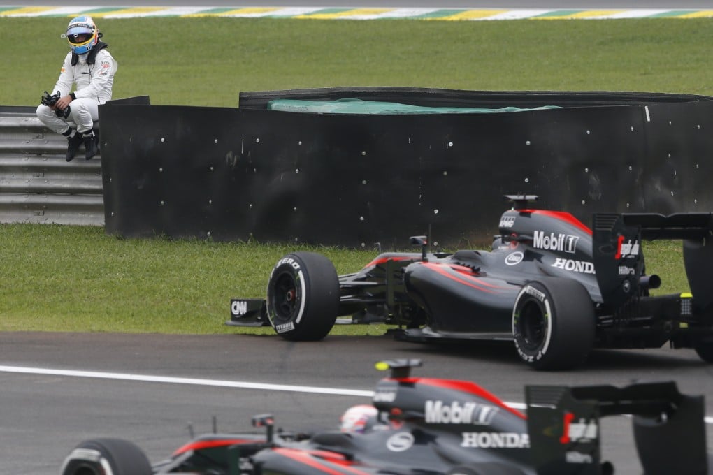 McLaren driver Fernando Alonso, of Spain, sits on the guardrail, waiting for a lift back to pits after crashing during practice at the Brazilian Grand Prix. Photo: AP
