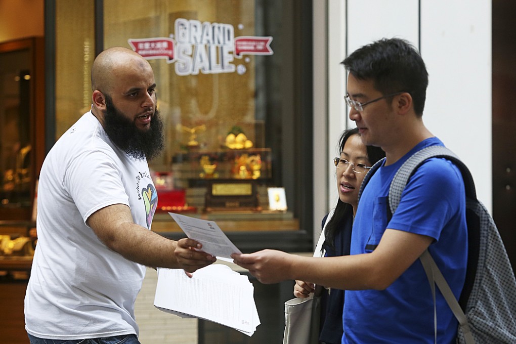 Adeel Malik hands out copies of the Muslim Council of Hong Kong's letter of peace condemning the terror attacks in Paris along Park Lane in Tsim Sha Tsui. Photo: Sam Tsang
