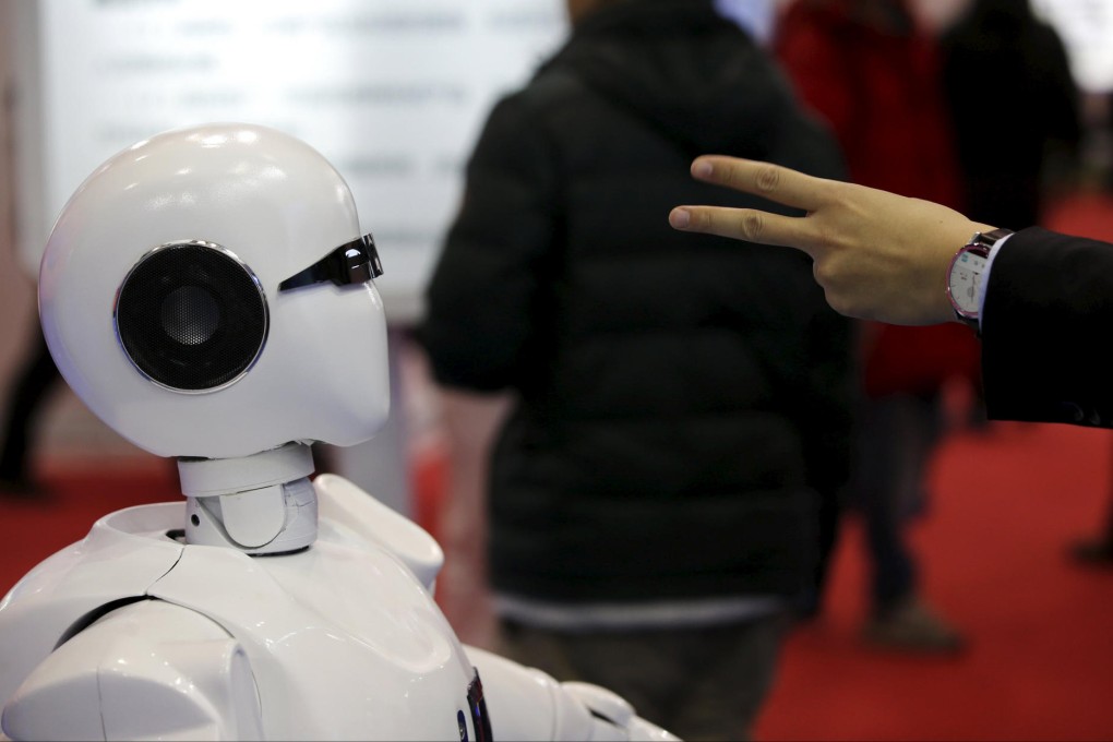 A visitor gestures to an android at the World Robot Conference in Beijing, where China showcased a version of its space robot. Photo: Reuters