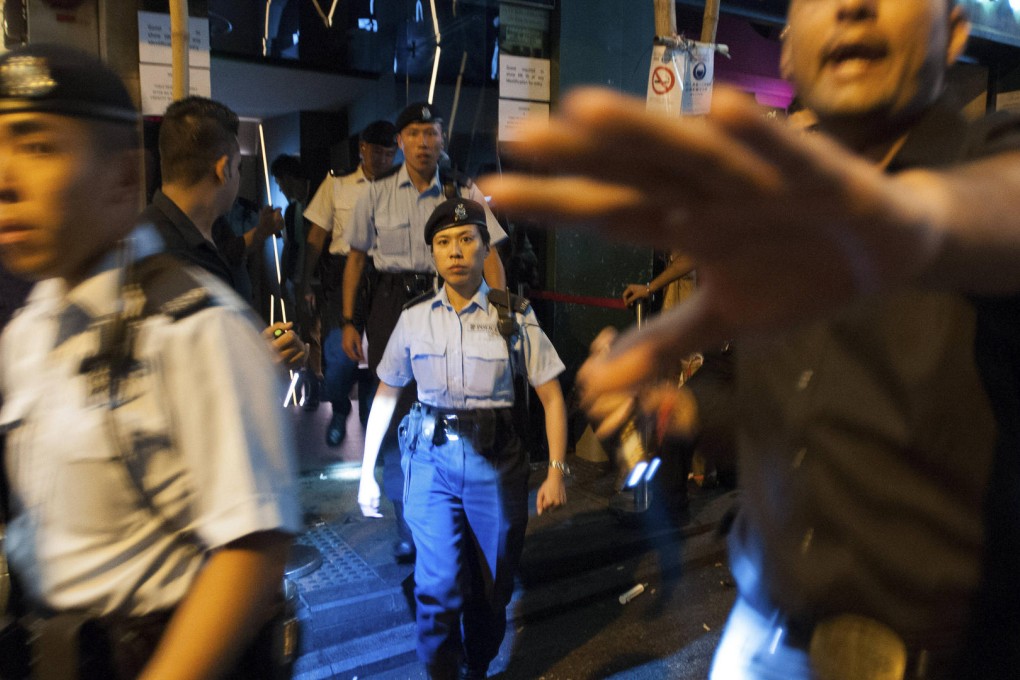 A bouncer at Lan Kwai Fong club Volar tries to hold people back as undercover and uniformed police officers exit the premises after searching customers for drugs in the early hours of September 19.