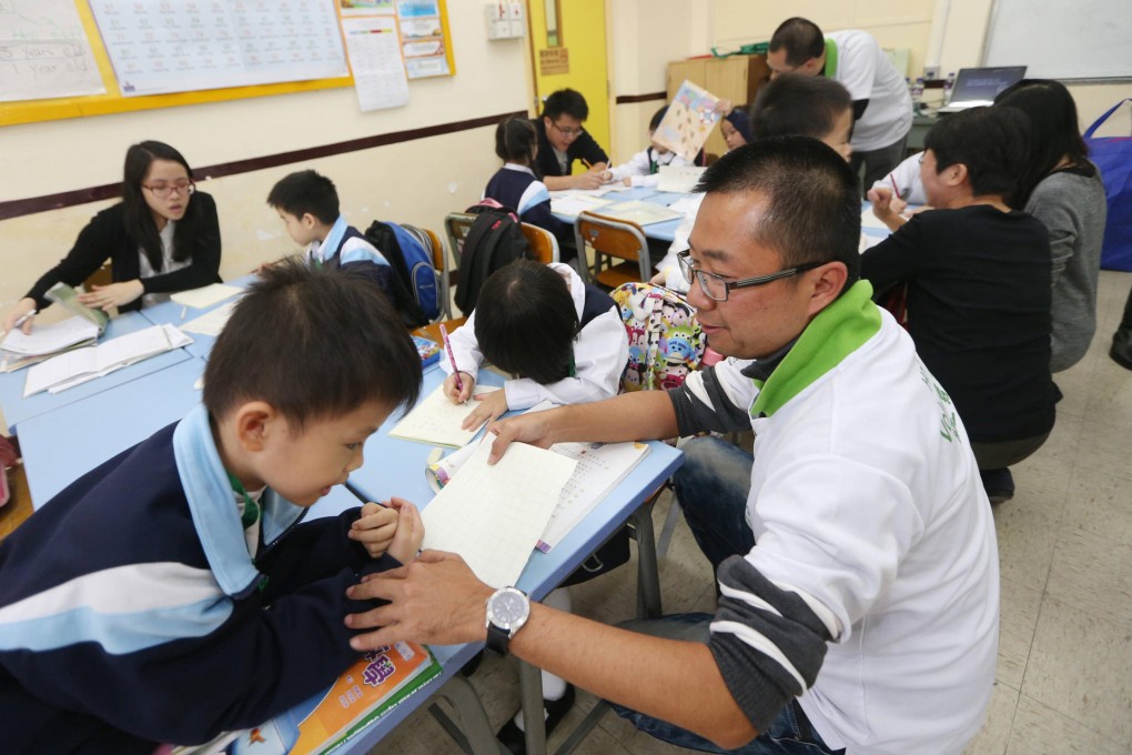 Boot Wong, one of six Hang Seng Bank volunteers, helps a young pupil with his homework at the Sham Shui Po school. Photo: David Wong