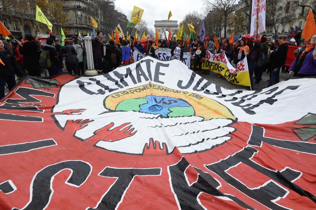 Activists hold up a giant banner calling for "climate justice" during a demonstration near the Arc de Triomphe in Paris. Photo: AFP