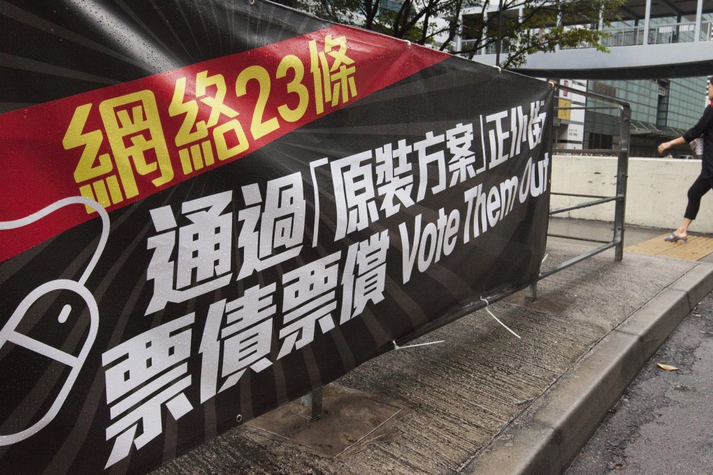 A person walks by a banner protesting against Internet Article 23 outside the Legco complex. Photo: EPA