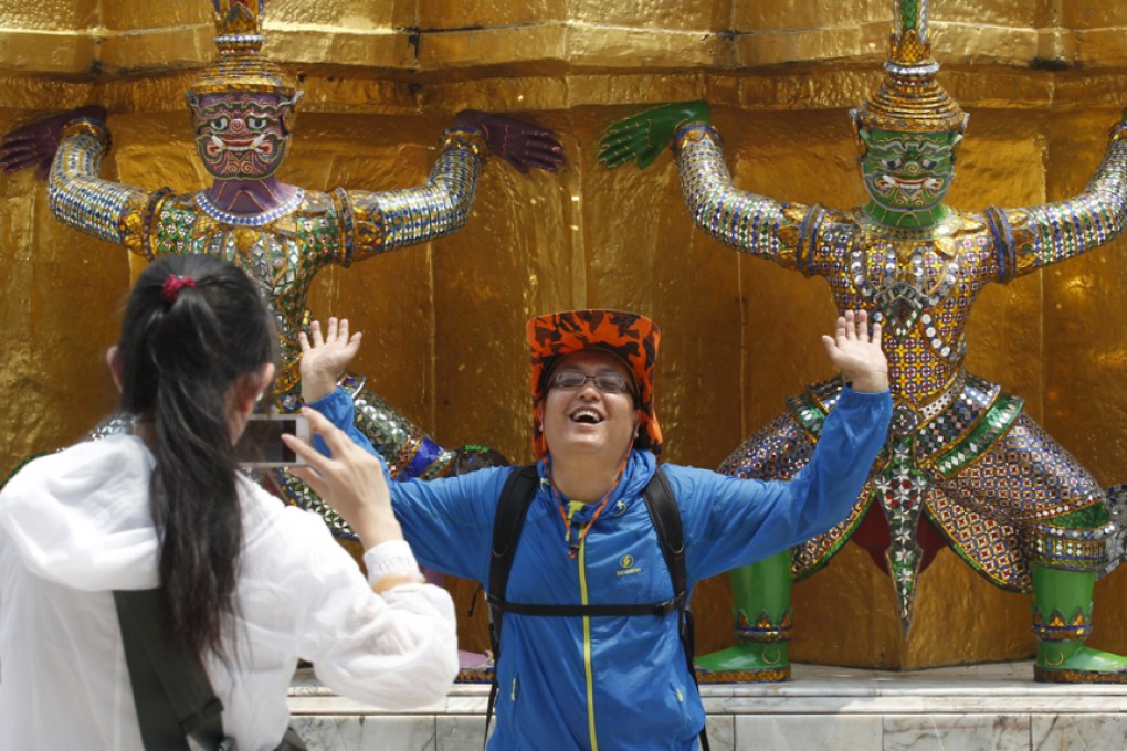 A Chinese tourist strikes a similar pose to statues as they visit the Grand Palace in Bangkok. Public outrage forced the Thai government to issue thousands of Chinese-language etiquette manuals last year in an effort to ensure sightseers behave themselves. Photo: Reuters