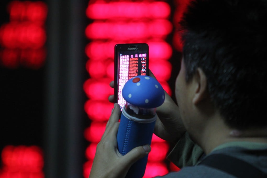 A Chinese investor takes a smartphone photo of electronic displays showing stock prices in a brokerage house in Beijing. Photo: AP