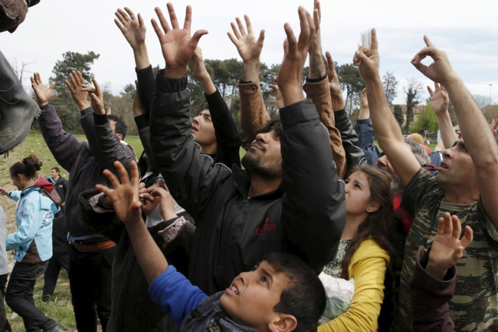Migrants and refugees reach out to get humanitarian aid at a makeshift camp at the Greek-Macedonian border near the village of Idomeni, Greece. Photos: Reuters