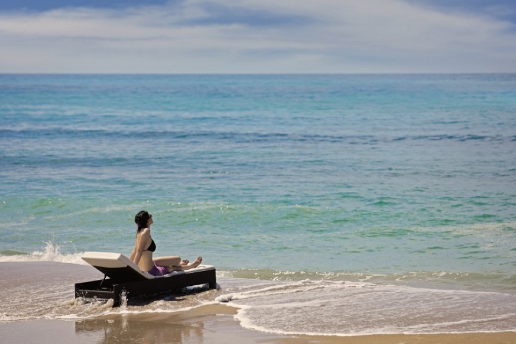 A tourist enjoys the great ocean views in a beach in Sanya.