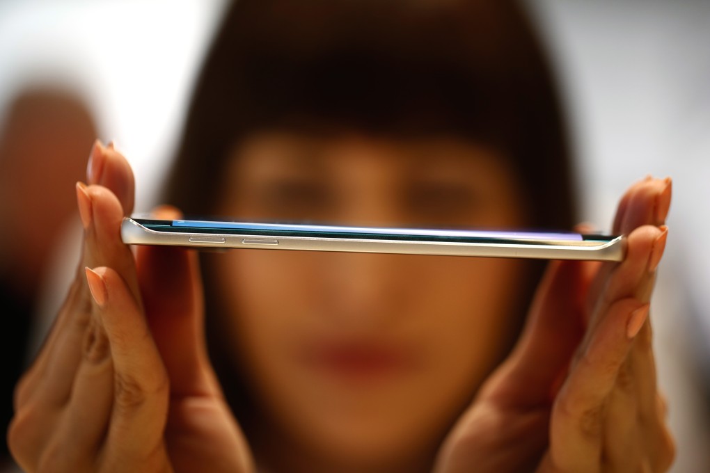 An employee shows the curved screen of a Galaxy S6 Edge smartphone device. Photo: Simon Dawson/Bloomberg/Getty Images